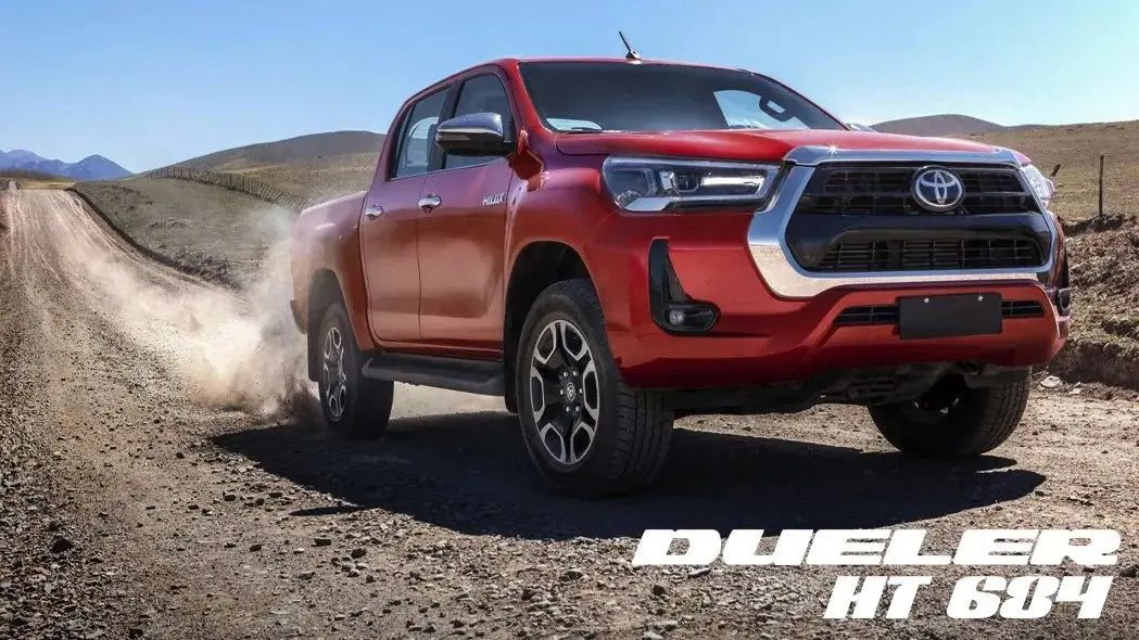 Picape vermelha com pneus Bridgestone Dueler em estrada de terra